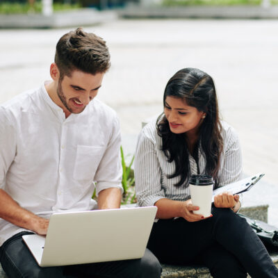 Positive business people discussing information on laptop screen when working outdoors